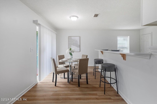 dining space featuring a textured ceiling and light hardwood / wood-style flooring