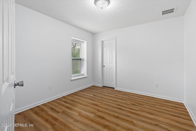 unfurnished room featuring a textured ceiling and hardwood / wood-style floors