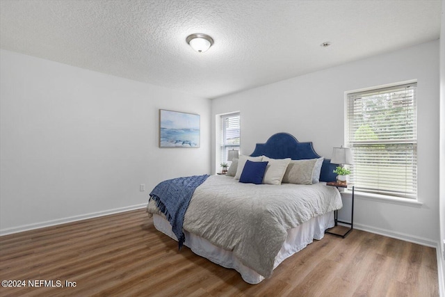 bedroom with multiple windows, a textured ceiling, and hardwood / wood-style flooring