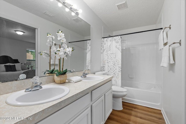 full bathroom with vanity, shower / bath combo, wood-type flooring, a textured ceiling, and toilet