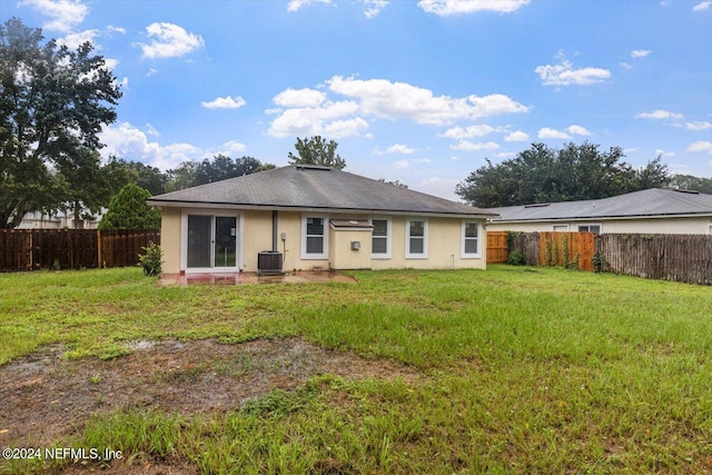 back of property featuring a lawn and central AC