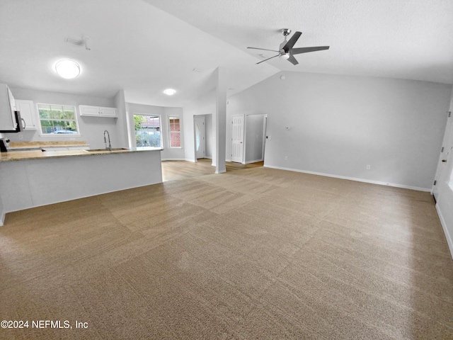 unfurnished living room with lofted ceiling, ceiling fan, light colored carpet, and sink