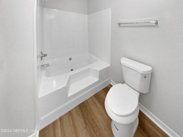 bathroom with toilet,  shower combination, and hardwood / wood-style flooring