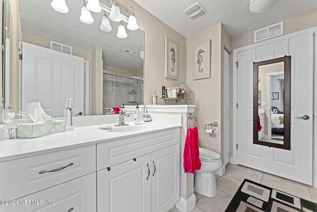 bathroom with vanity, a textured ceiling, tile patterned flooring, a shower with door, and toilet