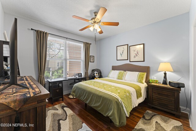 bedroom with a textured ceiling, dark wood-type flooring, and ceiling fan