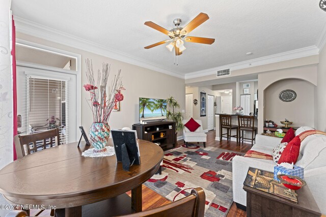 living room featuring a textured ceiling, ceiling fan, hardwood / wood-style floors, and crown molding