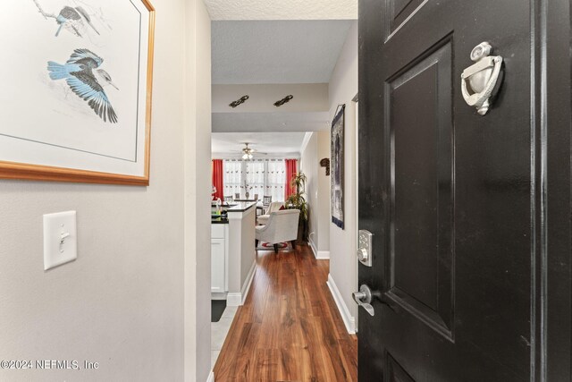 corridor featuring a textured ceiling and dark hardwood / wood-style floors