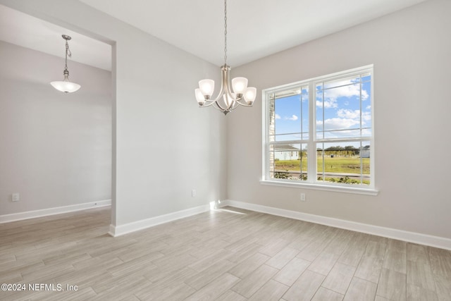 spare room with light hardwood / wood-style flooring and a chandelier