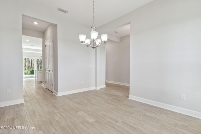 empty room with a notable chandelier and light wood-type flooring