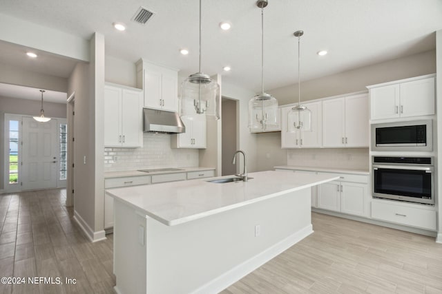 kitchen featuring appliances with stainless steel finishes, hanging light fixtures, white cabinetry, an island with sink, and sink