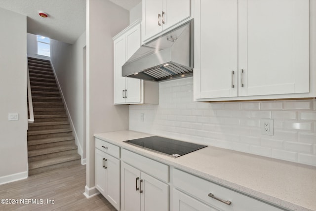 kitchen featuring black electric cooktop, light hardwood / wood-style flooring, decorative backsplash, and white cabinetry