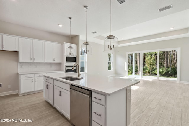 kitchen with appliances with stainless steel finishes, pendant lighting, an island with sink, and white cabinets