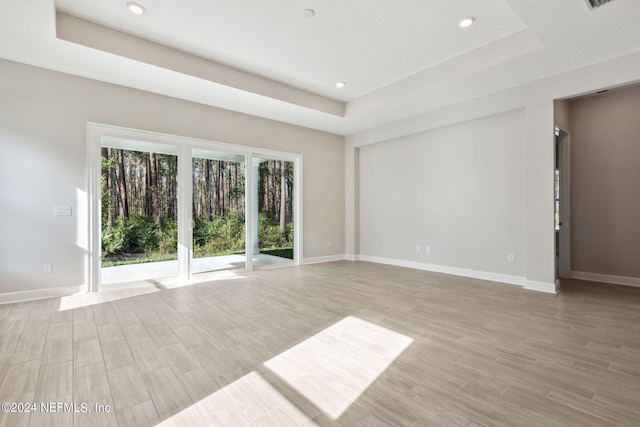 spare room with a raised ceiling and light hardwood / wood-style floors