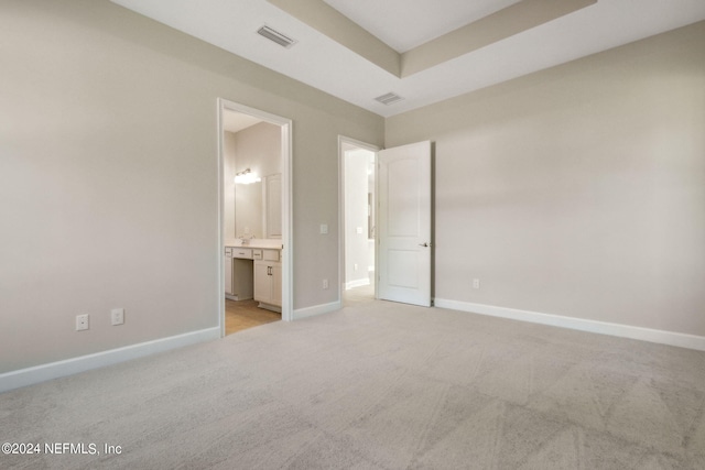 unfurnished bedroom featuring connected bathroom and light colored carpet