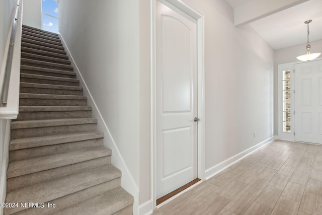 foyer featuring beamed ceiling, light hardwood / wood-style flooring, and a wealth of natural light