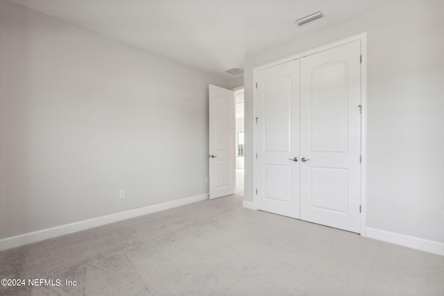 unfurnished bedroom featuring light carpet and a closet