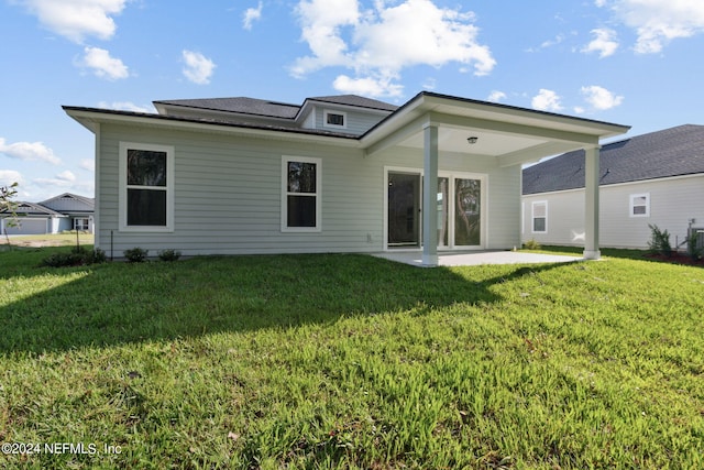 rear view of house with a patio and a lawn