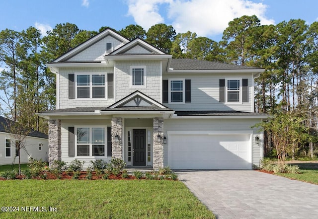 view of front of house with stone siding, a front yard, driveway, and a garage