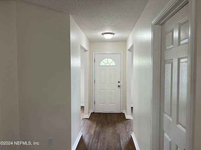 doorway featuring a textured ceiling and dark hardwood / wood-style floors