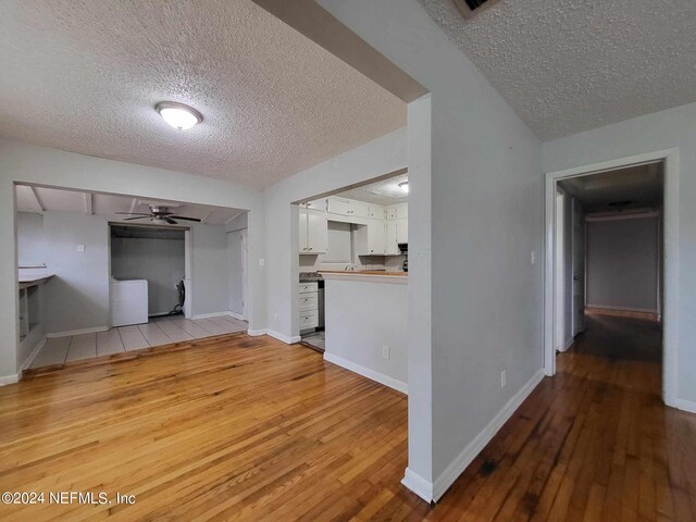 unfurnished living room featuring a textured ceiling, ceiling fan, and light hardwood / wood-style flooring