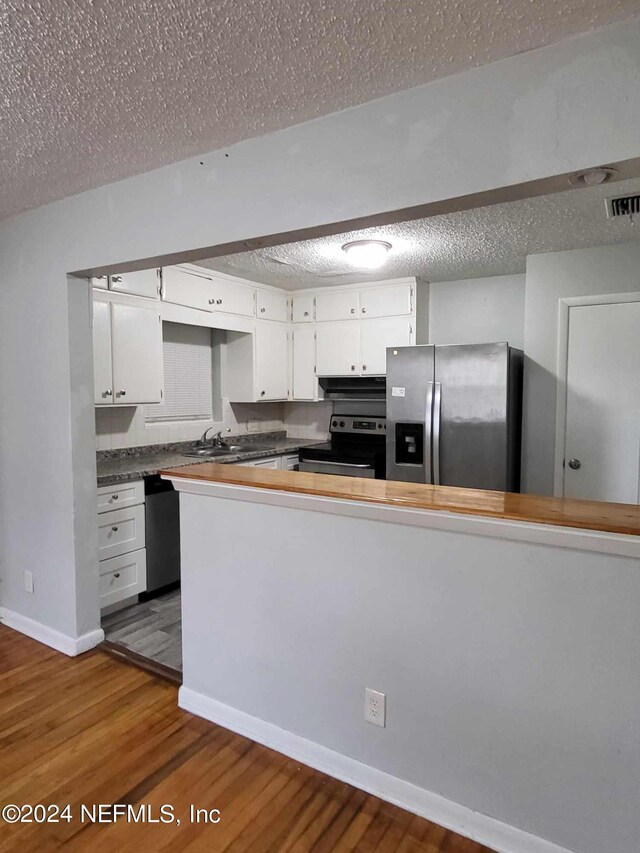 kitchen featuring white cabinetry, stainless steel appliances, a textured ceiling, hardwood / wood-style flooring, and sink