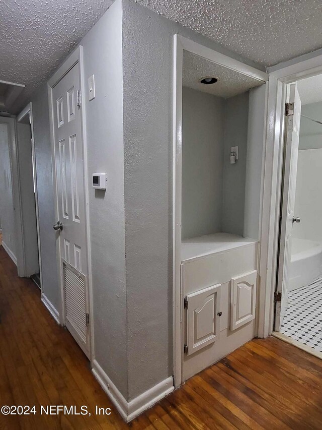 hallway featuring a textured ceiling and dark hardwood / wood-style flooring