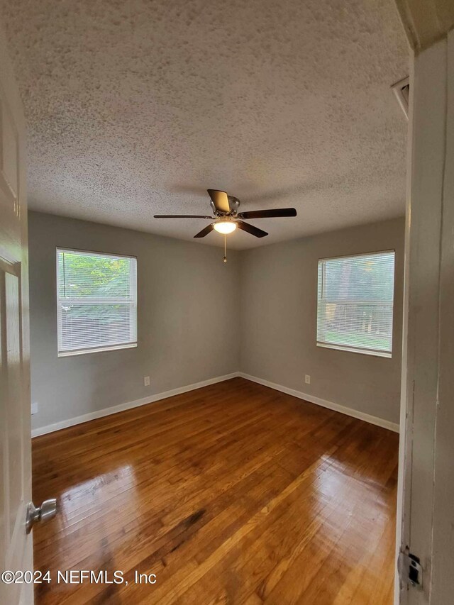 spare room with ceiling fan, hardwood / wood-style flooring, and a textured ceiling