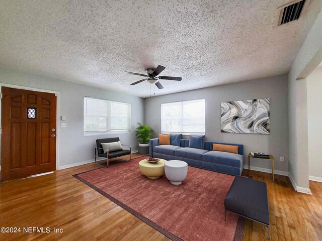 living room featuring a textured ceiling, hardwood / wood-style floors, and ceiling fan