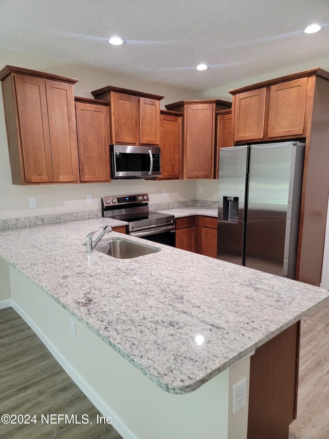 4144 Quiet Creek Loop Unit 130, Middleburg, FL 32068 - kitchen featuring brown cabinets, a peninsula, stainless steel appliances, and light wood-type flooring