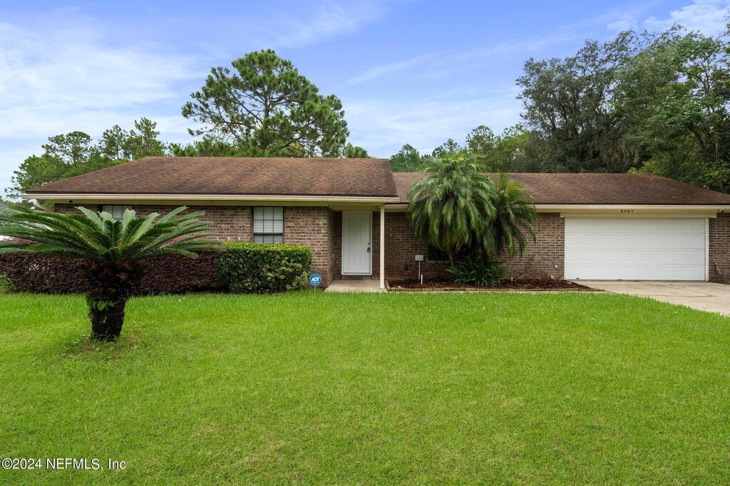 ranch-style house featuring a garage and a front lawn