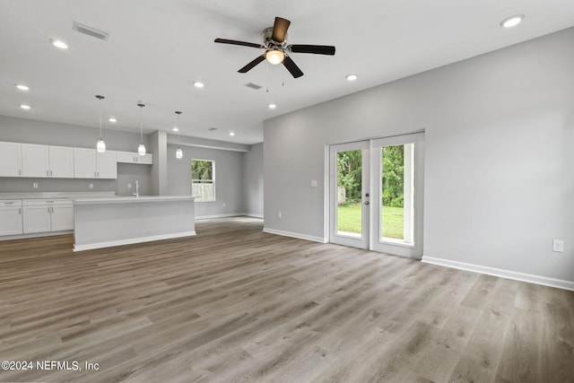 unfurnished living room with sink, ceiling fan, and light hardwood / wood-style floors