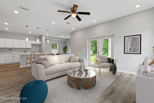 living room featuring light hardwood / wood-style flooring, ceiling fan, and french doors