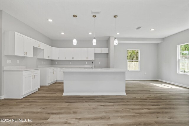 kitchen featuring white cabinetry, an island with sink, sink, and light hardwood / wood-style floors