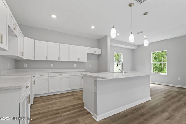 kitchen with decorative light fixtures, white cabinets, dark hardwood / wood-style flooring, and a kitchen island with sink