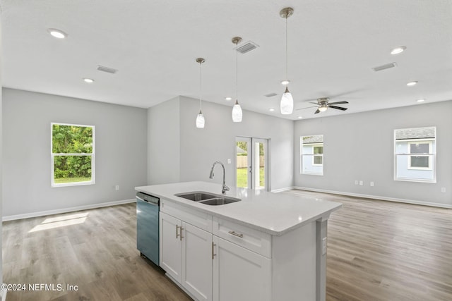 kitchen featuring pendant lighting, white cabinetry, sink, stainless steel dishwasher, and light hardwood / wood-style floors