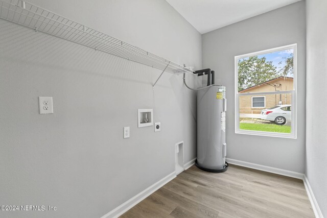 clothes washing area with hookup for a washing machine, hookup for an electric dryer, light hardwood / wood-style floors, and electric water heater