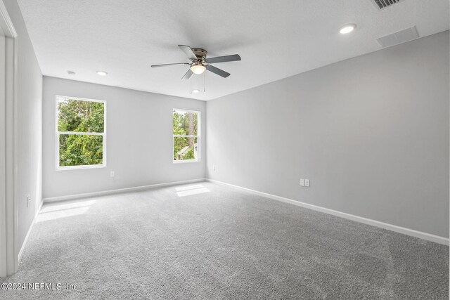 unfurnished room with a textured ceiling, ceiling fan, and carpet