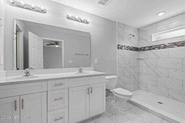 bathroom featuring vanity, ceiling fan, toilet, and a tile shower