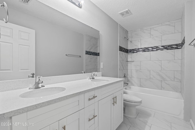 full bathroom with a textured ceiling, vanity, toilet, and tiled shower / bath