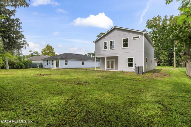 rear view of property with cooling unit and a yard