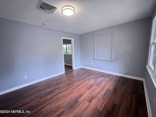 spare room featuring a textured ceiling and dark wood-type flooring