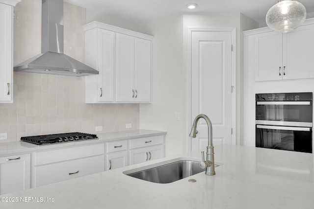 kitchen with white cabinetry, stainless steel gas stovetop, sink, and wall chimney range hood