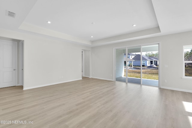 spare room with light hardwood / wood-style floors and a tray ceiling