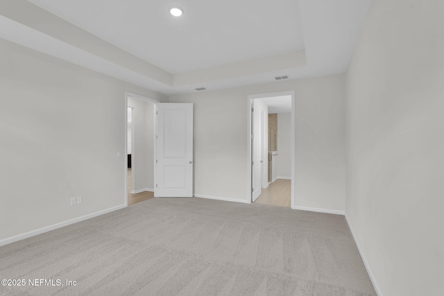 spare room with light colored carpet and a tray ceiling