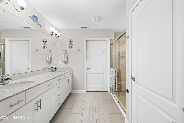 bathroom featuring vanity, a textured ceiling, and a shower with door