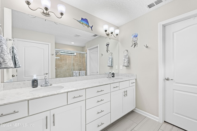 bathroom with a shower with shower door, vanity, and a textured ceiling