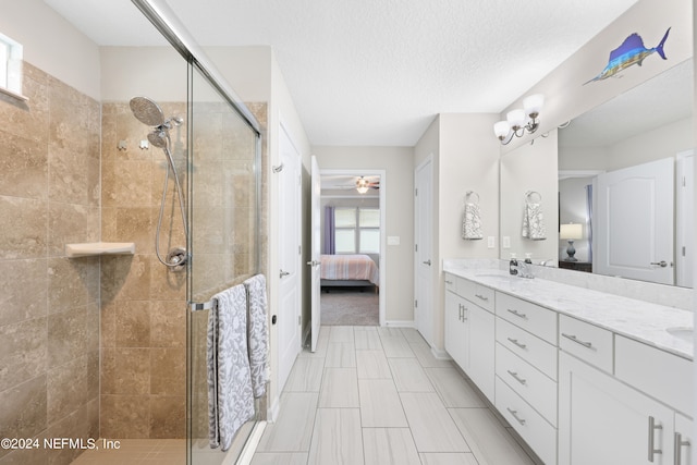 bathroom with ceiling fan, vanity, a shower with shower door, and a textured ceiling