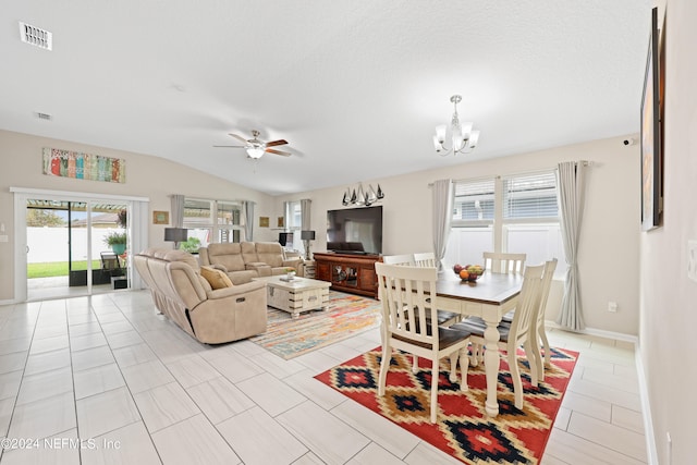 tiled living room with ceiling fan with notable chandelier, lofted ceiling, and a textured ceiling