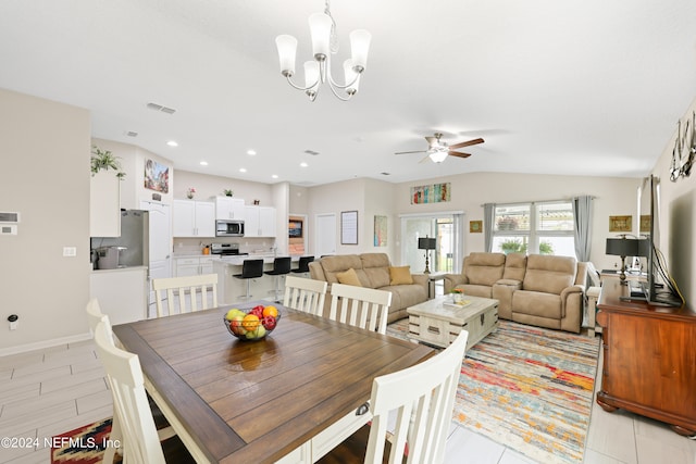 tiled dining space featuring ceiling fan with notable chandelier and lofted ceiling