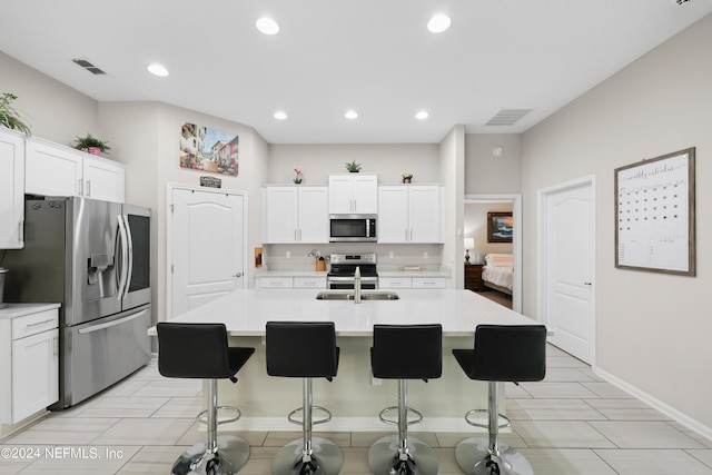 kitchen featuring an island with sink, a kitchen bar, white cabinetry, and appliances with stainless steel finishes